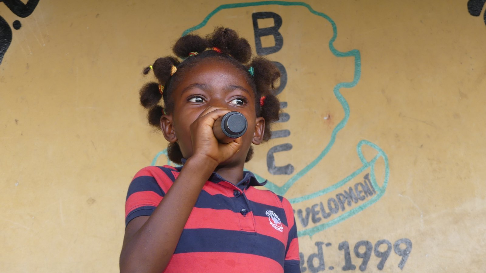 A child singing into a microphone at a Ray Foundation Christmas celebration in Sierra Leone